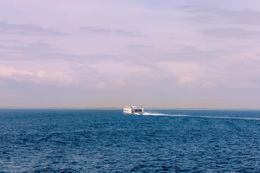 Seascape with a white ferry in the distance and waves. Sea transport