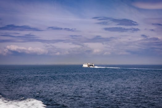 Seascape with a white ferry in the distance and waves. Sea transport