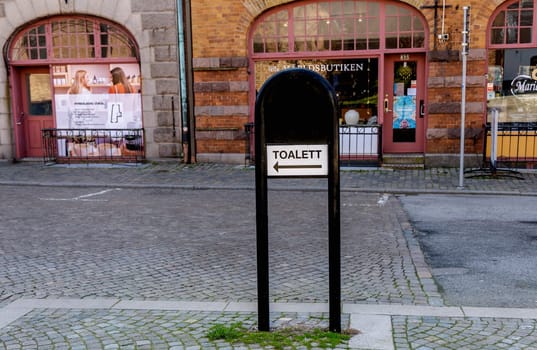 Sign in the city with the inscription in Swedish - toilet. Street sign. Ystad, Sweden - May 15, 2024.