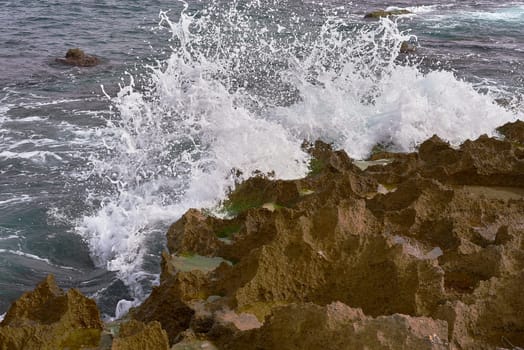 Embrace the luminous ambiance of a sunlit day as waves gently caress the rocky shore, casting a radiant glow on the coastal landscape, a captivating tableau of natural elegance and tranquility