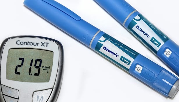 Blood sugar meter with test strips indicates high blood sugar levels and Ozempic injection pen for diabetes. Denmark - February 10, 2024