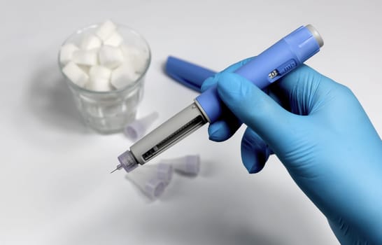 Hands in blue surgical gloves holding Ozempic Insulin injection pen for diabetics.