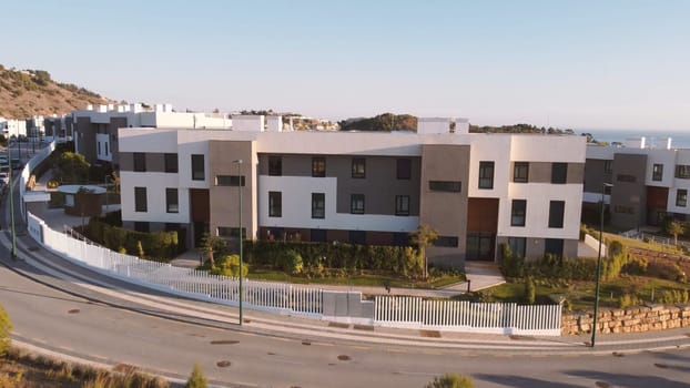 An aerial view showcasing a dense residential area with numerous buildings, asphalt roads, land lots, houses, trees, grass, and an urban design landscape featuring diverse facades.