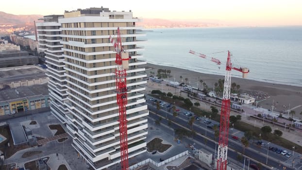 An urban design skyscraper under construction near the ocean, complemented by the stunning landscape and vast sky.