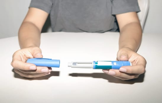 Female hands holding an insulin pen. Ozempic Insulin injection pen or insulin cartridge pen for diabetics. Medical equipment for diabetes parients.