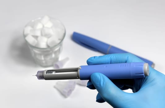 Hands in blue surgical gloves holding Ozempic Insulin injection pen for diabetics.