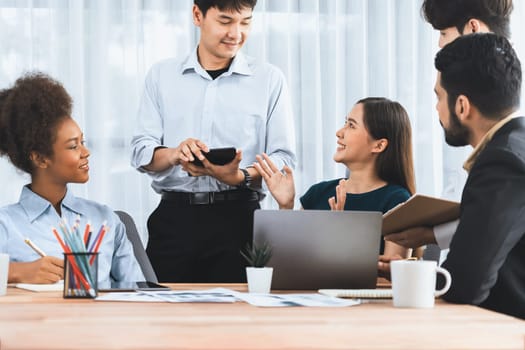 Multiracial analyst team use BI dashboard data to analyze financial report on meeting table. Group of diverse business people utilize data analysis by FIntech for business marketing decision. Concord