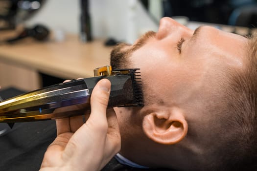 Barbers skilled hand deftly trims a clients beard using a precision trimmer in the barbershop