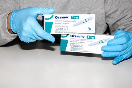 Hands in blue surgical gloves holds a package with Ozempic Insulin injection pen for diabetics. Denmark - February 10, 2024