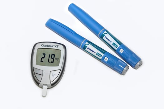 Blood sugar meter with test strips indicates high blood sugar levels and Ozempic injection pen for diabetes. Denmark - February 10, 2024