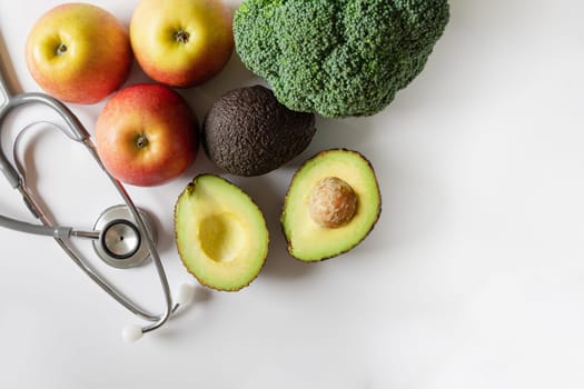 Healthy food concept. Fruit and vegetables and a statoscope laid out on a white background. High quality photo