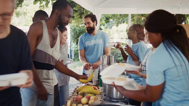 Voluntary individuals selflessly distribute free food to the needy, showing compassion and support in humanitarian charity event. Friendly volunteers offering hot meals and nourishments to the poor.