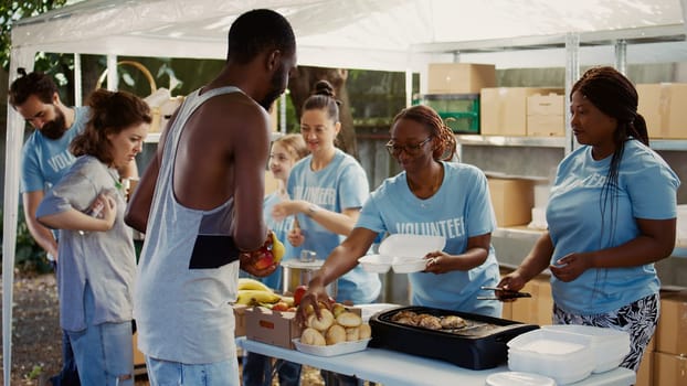 At homeless shelter, humanitarian aid group is involved in distribution of donations to those in need. Volunteers contribute by serving meals and offering assistance via a nonprofit food bank.