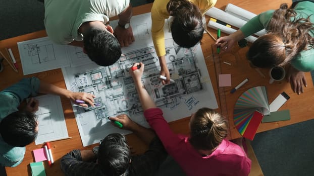 Top down view of civil engineer team writing at blueprint at meeting table with color palettes. Group of diverse people planning and taking a note while manager looking at project plans. Symposium.