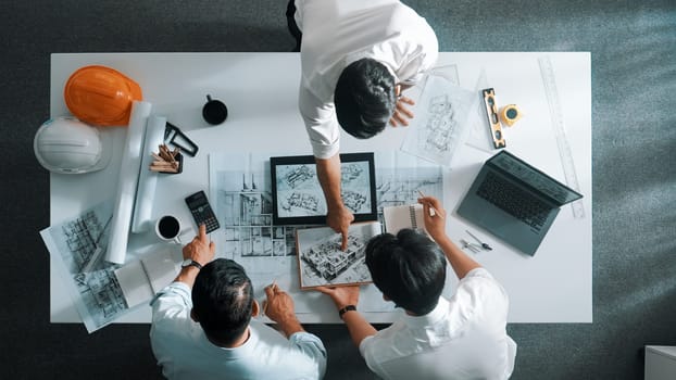 Top down view of professional manager look at plan while designer hold blueprint while present project to smart team. Top aerial view of smart team planning building structure together. Alimentation.