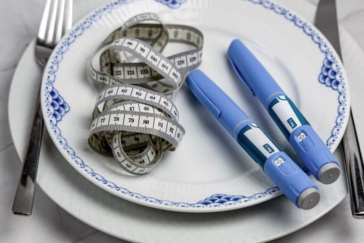 Ozempic Insulin injection pen or insulin cartridge pen for diabetics on a white plate. Medical equipment for diabetes parients.