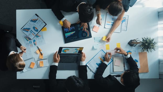 Top down aerial view of manager standing and present marketing plan to skilled investor. Diverse business team working together to analyze financial statistic graph at meeting table. Directorate.