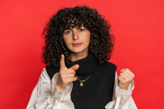 Quarrel. Displeased aggressive unhappy Caucasian young woman with curly hair gesturing hands with irritation and displeasure, blaming scolding for failure, asking why this happened on red background
