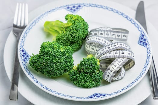 Concept of healthy eating and weight loss. Plate of green broccoli.