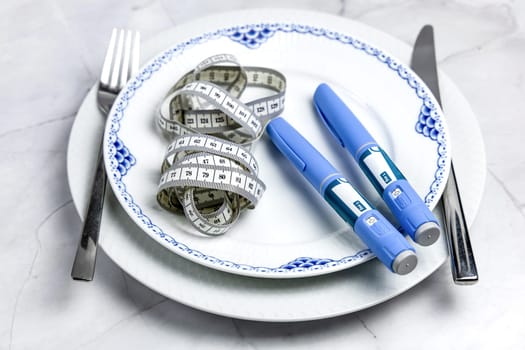 Ozempic Insulin injection pen or insulin cartridge pen for diabetics on a white plate. Medical equipment for diabetes parients.