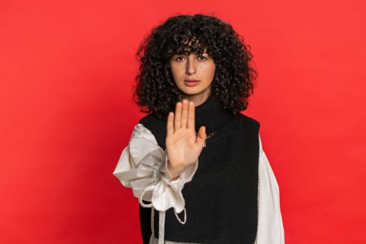 Stop, enough. Caucasian woman say no hold palm folded crossed hands in finish gesture, warning of finish prohibited access, declining communication, body language danger. Young girl on red background