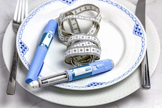 Ozempic Insulin injection pen or insulin cartridge pen for diabetics on a white plate. Medical equipment for diabetes parients.