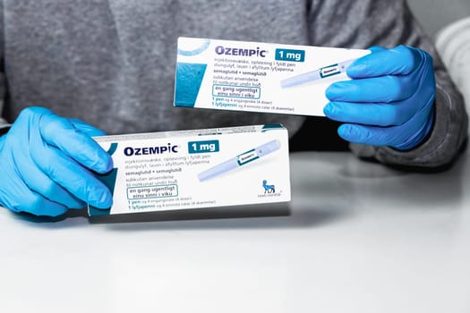 Hands in blue surgical gloves holds a package with Ozempic Insulin injection pen for diabetics. Denmark - February 10, 2024