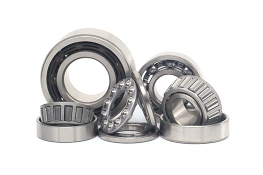 Array of bearings of varying sizes and types, including roller bearings and ball bearings isolated on a white background