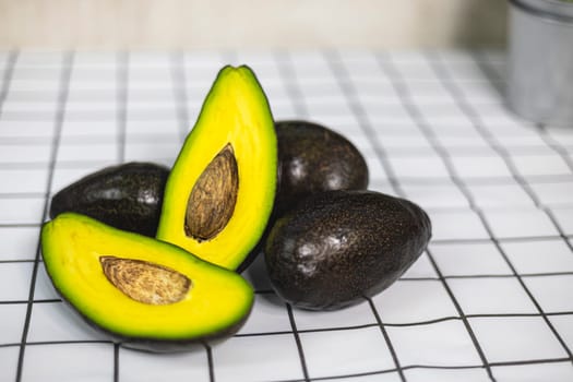 Whole and cut avocados on white table.