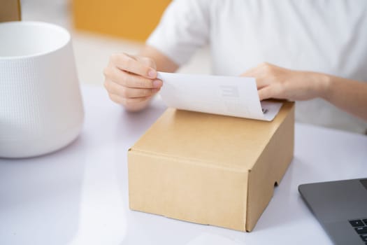 Closeup Male entrepreneur startup small business owner packing package preparing delivery parcel and attaching data label on carboard box on desk. Owener of small business packing product in boxes.