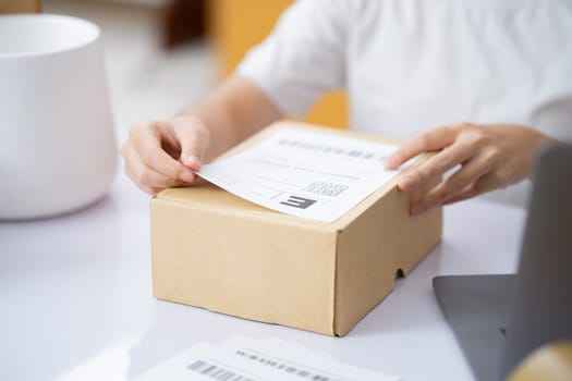 Closeup Male entrepreneur startup small business owner packing package preparing delivery parcel and attaching data label on carboard box on desk. Owener of small business packing product in boxes.