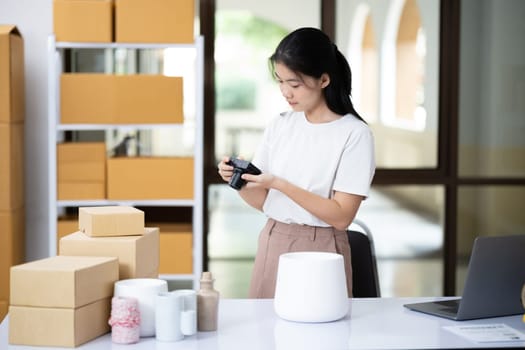 Young women taking photo of product with digital camera for post to sell online on the Internet and preparing pack product box. Selling online ideas concept