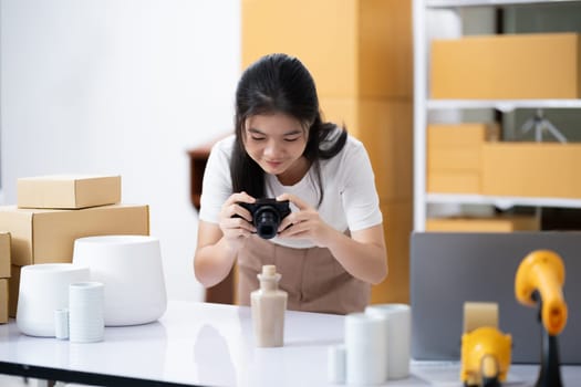 Young women taking photo of product with digital camera for post to sell online on the Internet and preparing pack product box. Selling online ideas concept