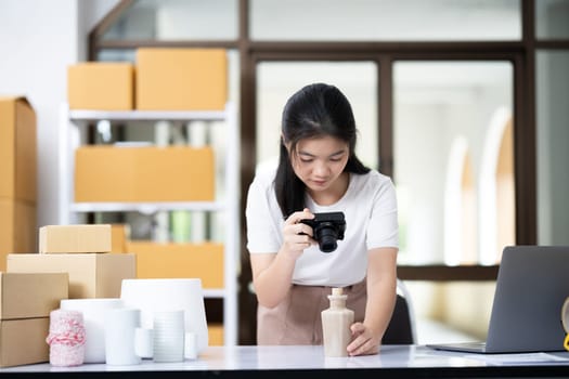 Young women taking photo of product with digital camera for post to sell online on the Internet and preparing pack product box. Selling online ideas concept