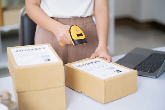 Hands scanning barcode on delivery parcel. Worker scan barcode of cardboard packages before delivery at storage. Woman working in factory warehouse scanning labels on the boxes with barcode scanner.