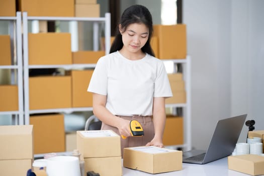 Hands scanning barcode on delivery parcel. Worker scan barcode of cardboard packages before delivery at storage. Woman working in factory warehouse scanning labels on the boxes with barcode scanner.