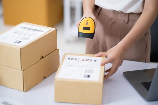 Hands scanning barcode on delivery parcel. Worker scan barcode of cardboard packages before delivery at storage. Woman working in factory warehouse scanning labels on the boxes with barcode scanner.