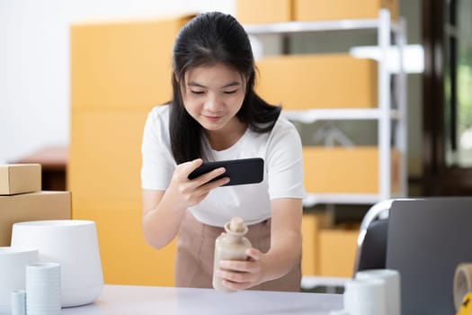 Young women taking photo of product with cell telephone or smartphone digital camera for post to sell online on the Internet and preparing pack product box. Selling online ideas concept