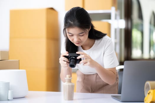 Young women taking photo of product with digital camera for post to sell online on the Internet and preparing pack product box. Selling online ideas concept