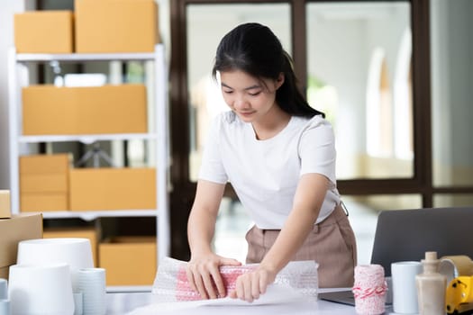 Young woman packing product for customer with cardboard box.