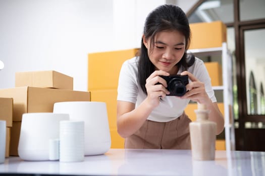 Young women taking photo of product with digital camera for post to sell online on the Internet and preparing pack product box. Selling online ideas concept