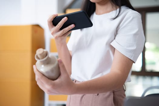 Young women taking photo of product with cell telephone or smartphone digital camera for post to sell online on the Internet and preparing pack product box. Selling online ideas concept