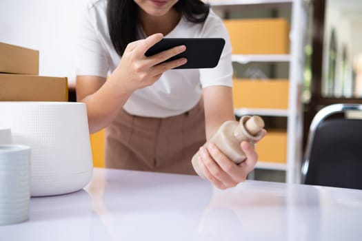 Young women taking photo of product with cell telephone or smartphone digital camera for post to sell online on the Internet and preparing pack product box. Selling online ideas concept