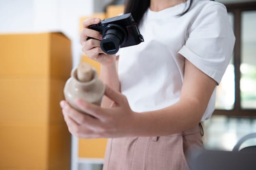 Young women taking photo of product with digital camera for post to sell online on the Internet and preparing pack product box. Selling online ideas concept