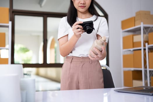 Young women taking photo of product with digital camera for post to sell online on the Internet and preparing pack product box. Selling online ideas concept