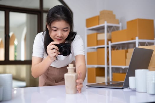 Young women taking photo of product with digital camera for post to sell online on the Internet and preparing pack product box. Selling online ideas concept