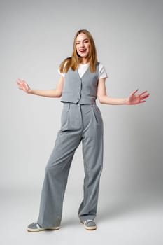 Joyful Young Blonde Woman Smiling against gray background in studio