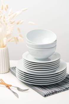 Stylish table setting with white dishware on white tablecloth close up