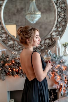 Portrait of a wealthy mature woman with evening makeup and hairstyle posing in a black dress against the backdrop of a Christmas room. Luxurious lifestyle. Cosmetology, plastic surgery, rejuvenation