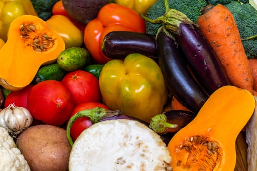 Various vegetables are laid out on a wooden table. Large assortment of vegetables food. pumpkin cabbage broccoli pepper tomatoes carrots and others.